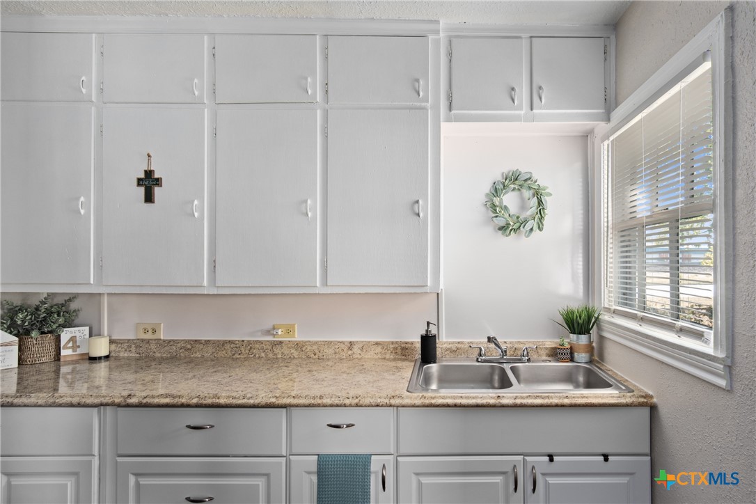 a kitchen with granite countertop white cabinets and a sink