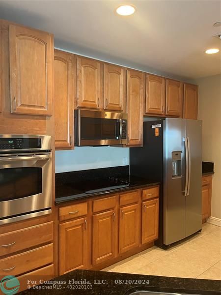 a kitchen with granite countertop a refrigerator stove and microwave