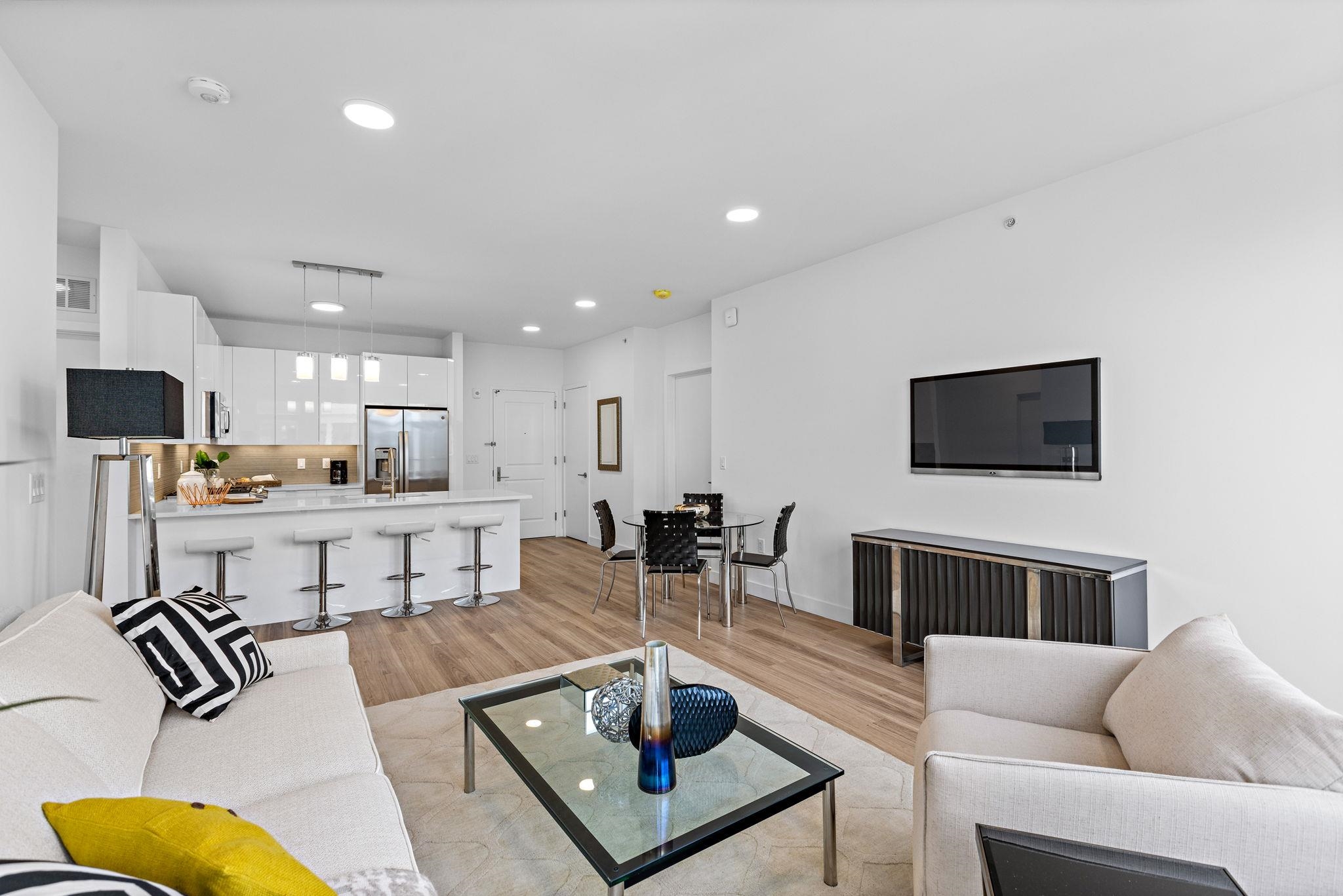 a living room with furniture a flat screen tv and kitchen view