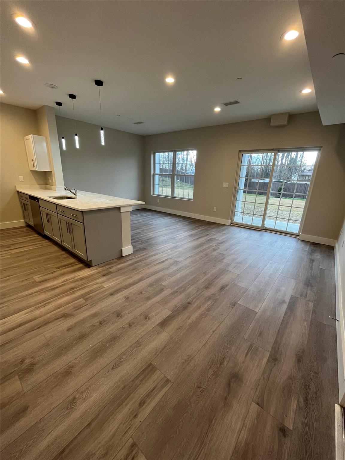 a view of an empty room with window and wooden floor