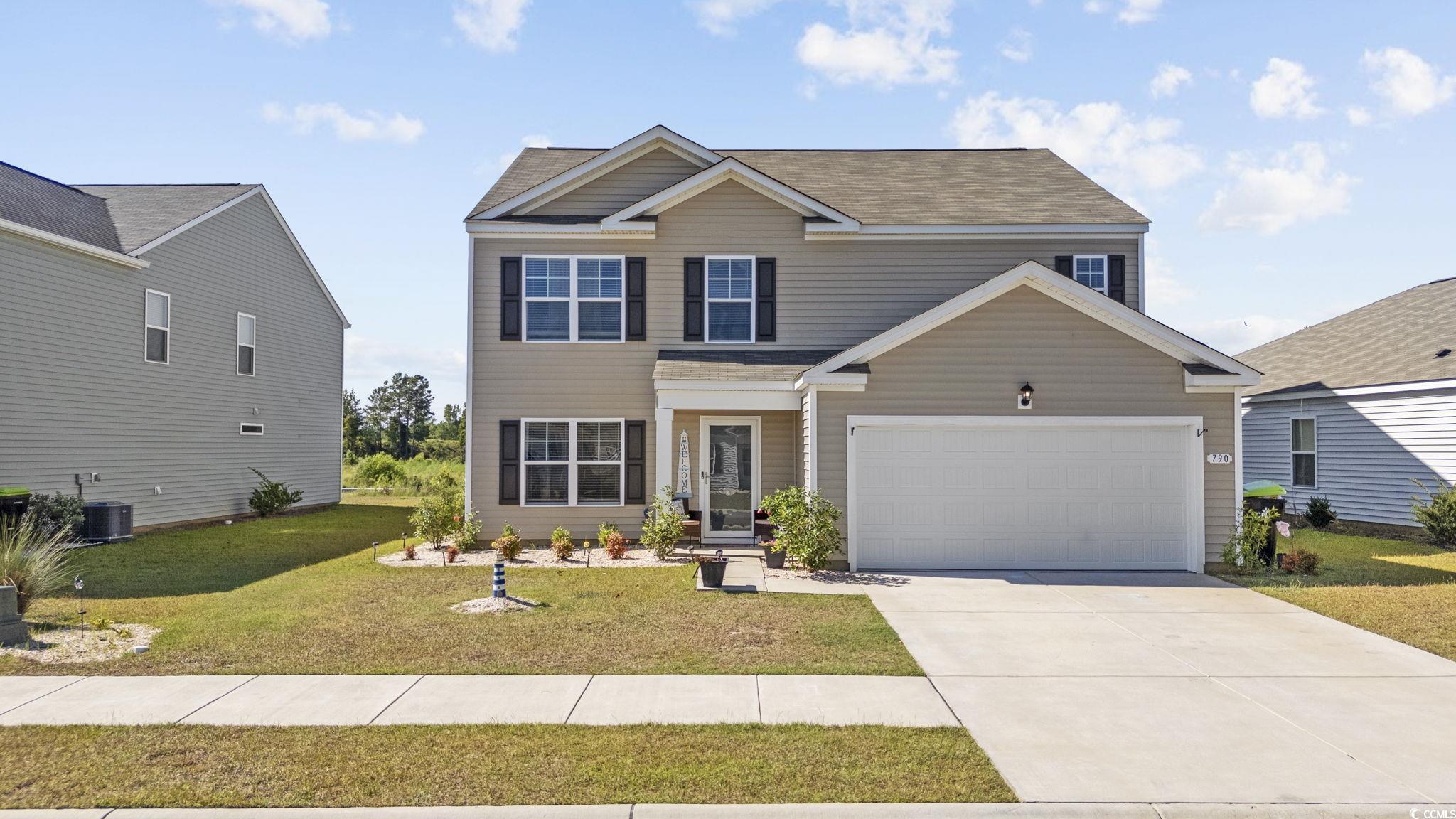 View of front facade featuring a front lawn, a gar