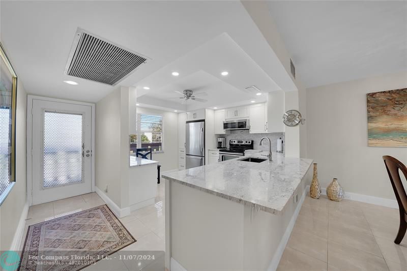 a view of kitchen with sink refrigerator and cabinets