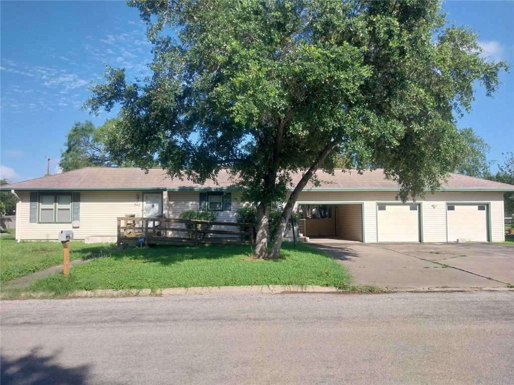 a front view of a house with a garden and a tree