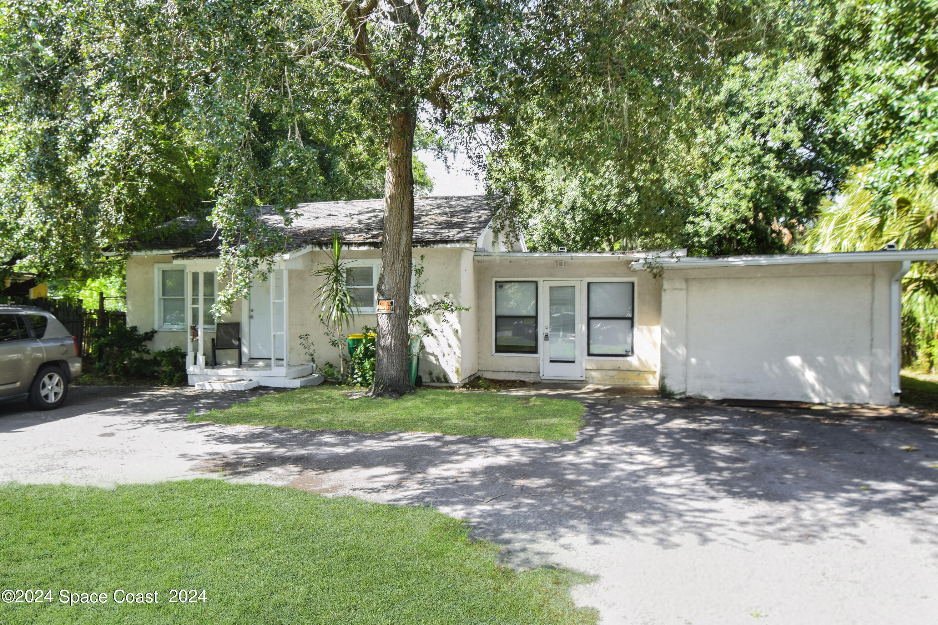 a view of a house with a yard and large trees