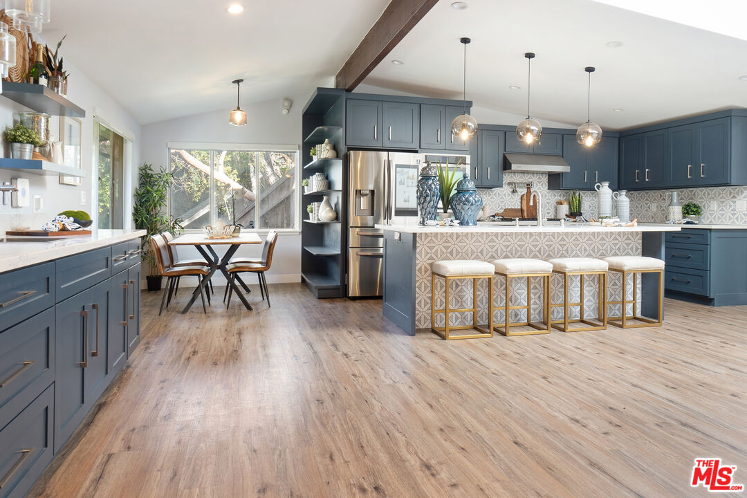 a living room with stainless steel appliances granite countertop furniture wooden floor and a view of kitchen