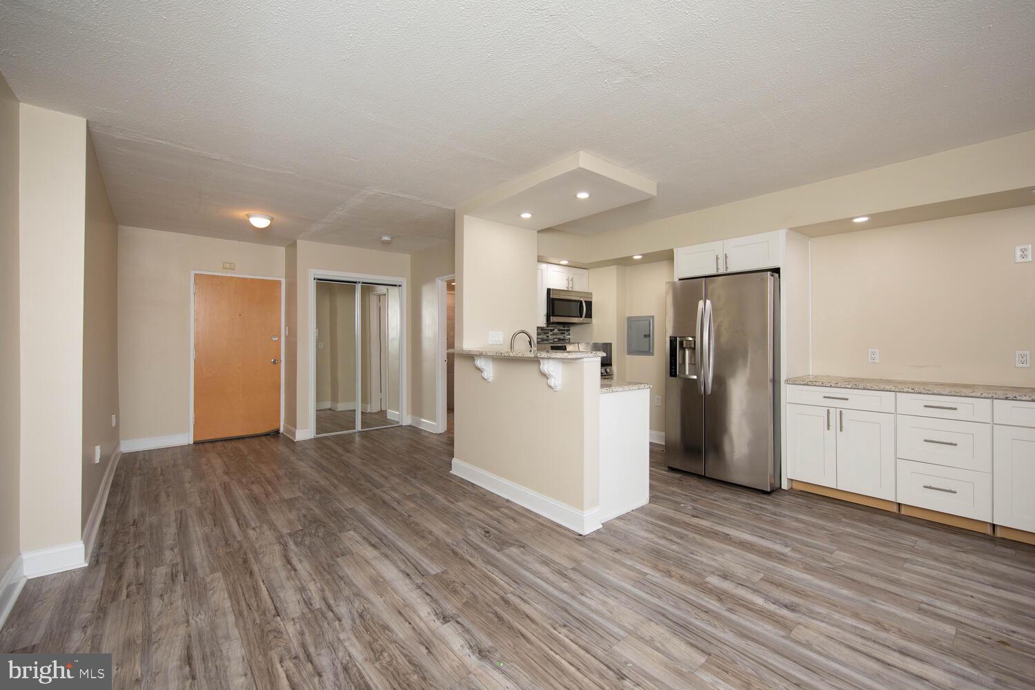 a view of a kitchen with refrigerator and wooden floor