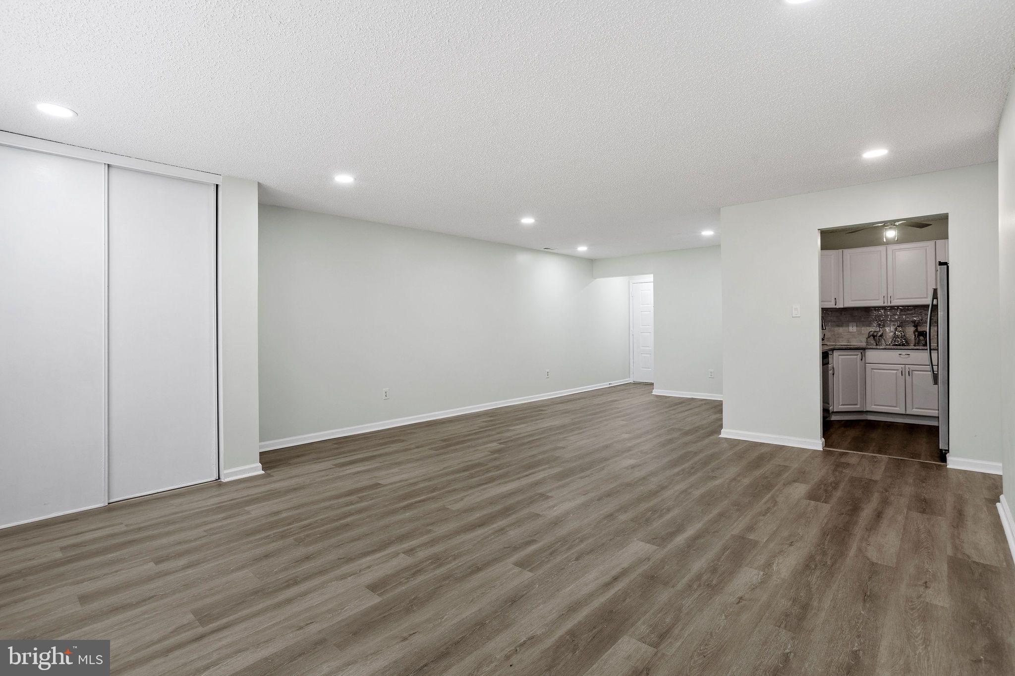 an empty room with wooden floor closet and windows