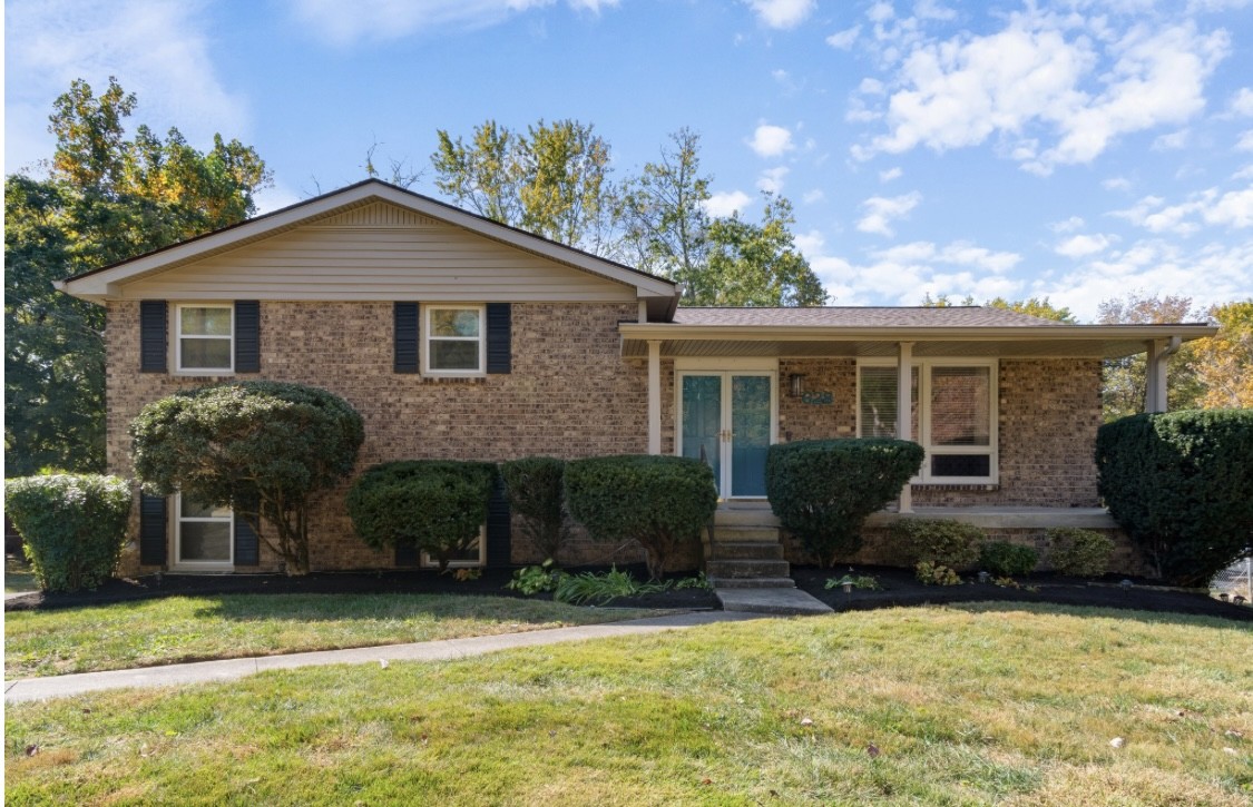 a front view of house with yard and trees in the background