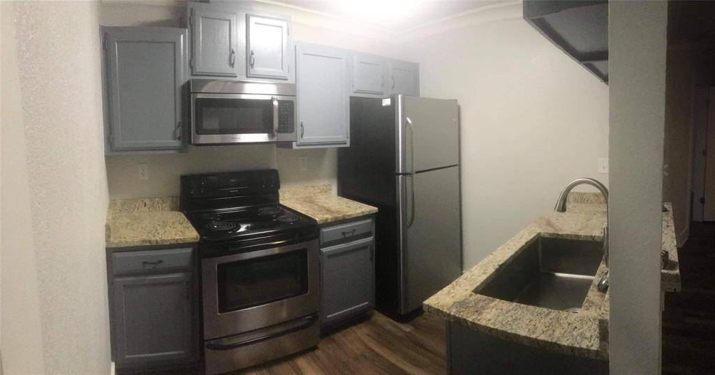 a kitchen with granite countertop white cabinets and stainless steel appliances