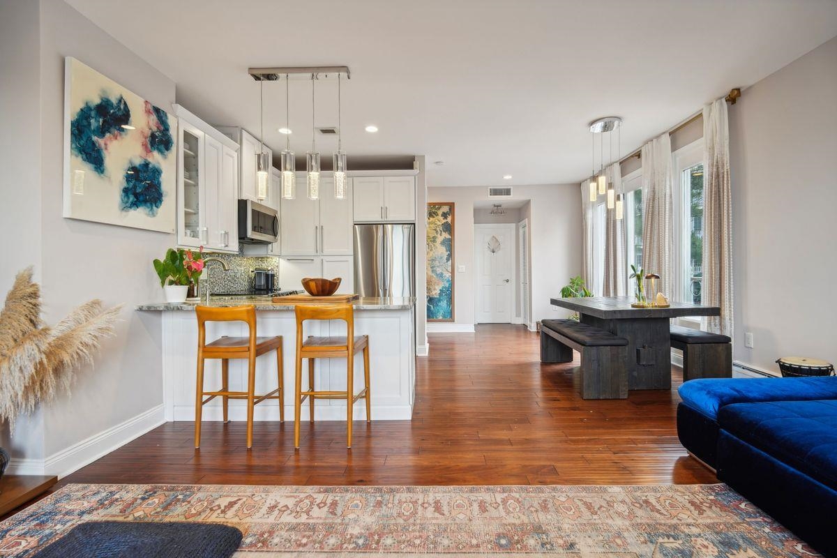 a living room with stainless steel appliances furniture a rug and a view of kitchen