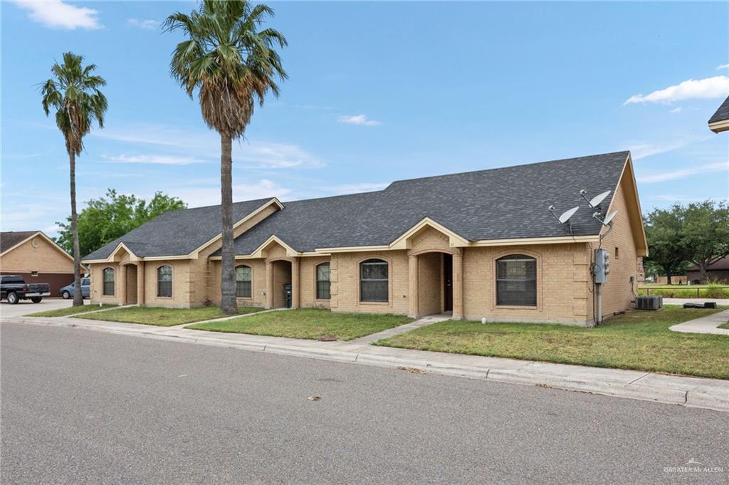 front view of a house with a yard and palm trees