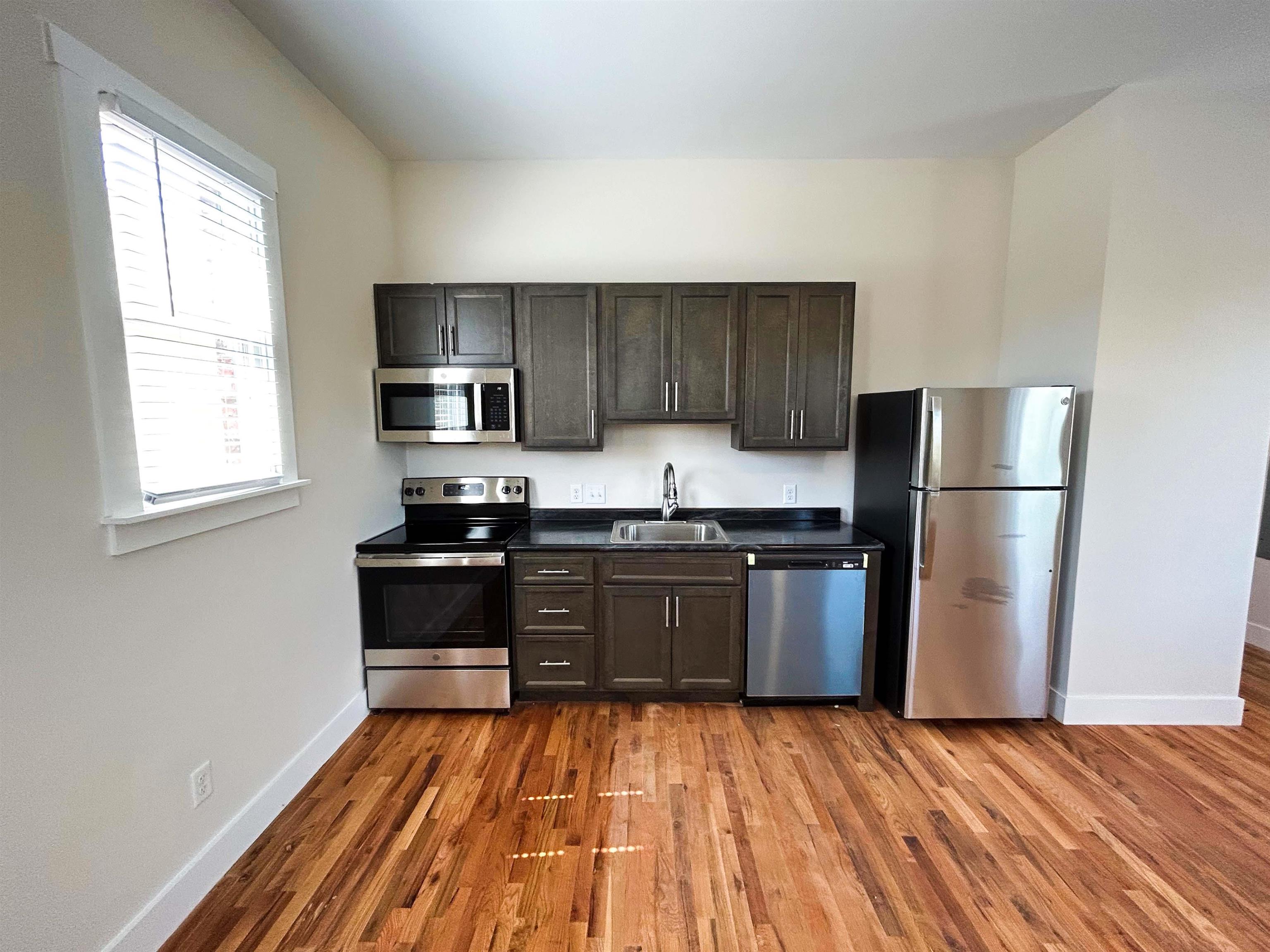 Kitchen with light hardwood / wood-style flooring, dark brown cabinets, appliances with stainless steel finishes, and sink