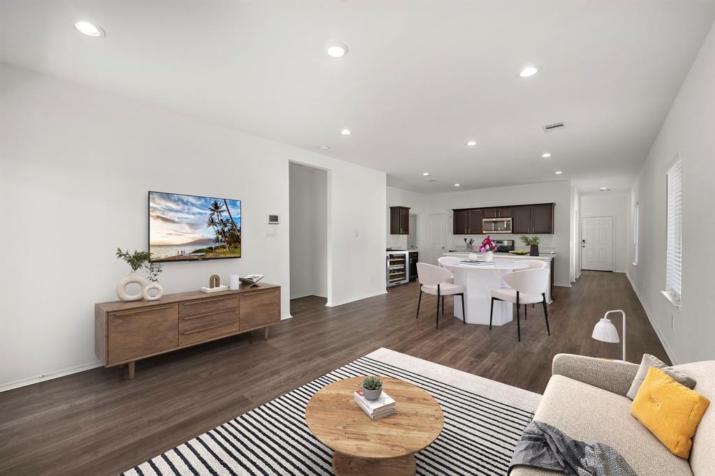 a living room with furniture and kitchen view with wooden floor