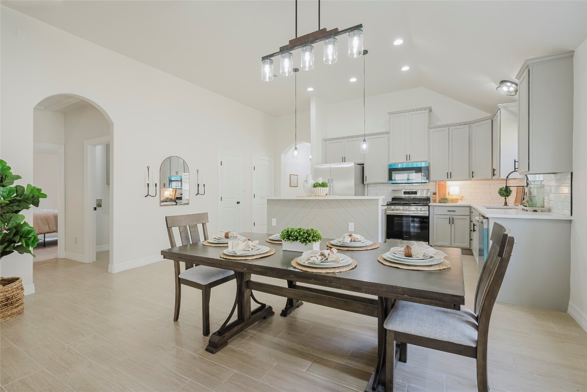 a kitchen with a dining table cabinets appliances and wooden floor