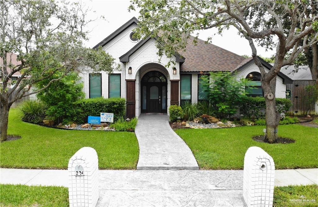 a front view of a house with garden and trees