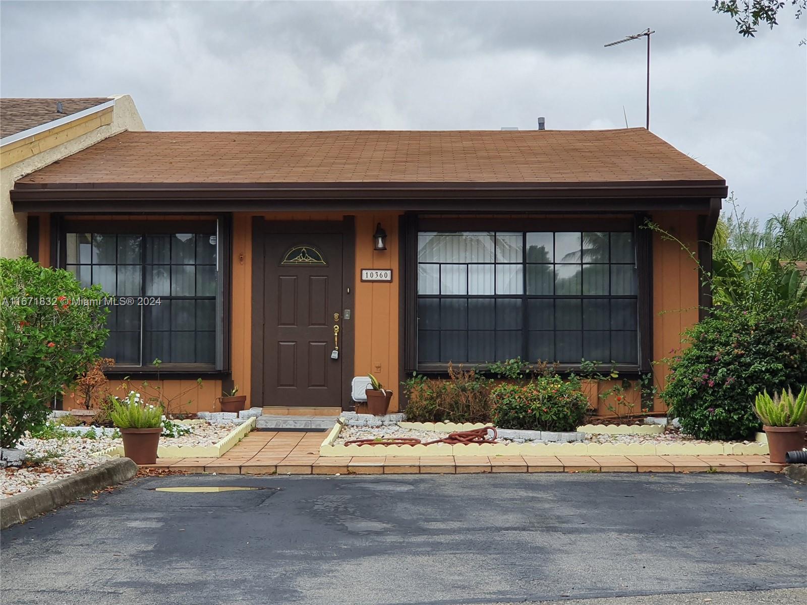 a front view of a house with a yard and potted plants