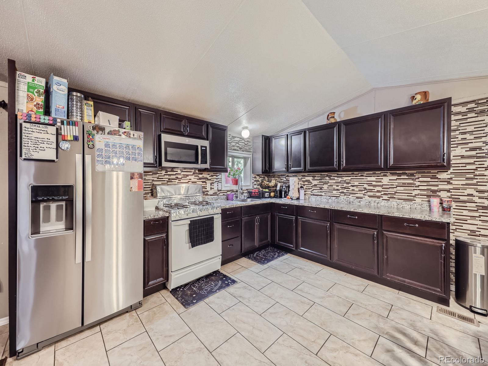 a kitchen with stainless steel appliances granite countertop a refrigerator and a stove top oven