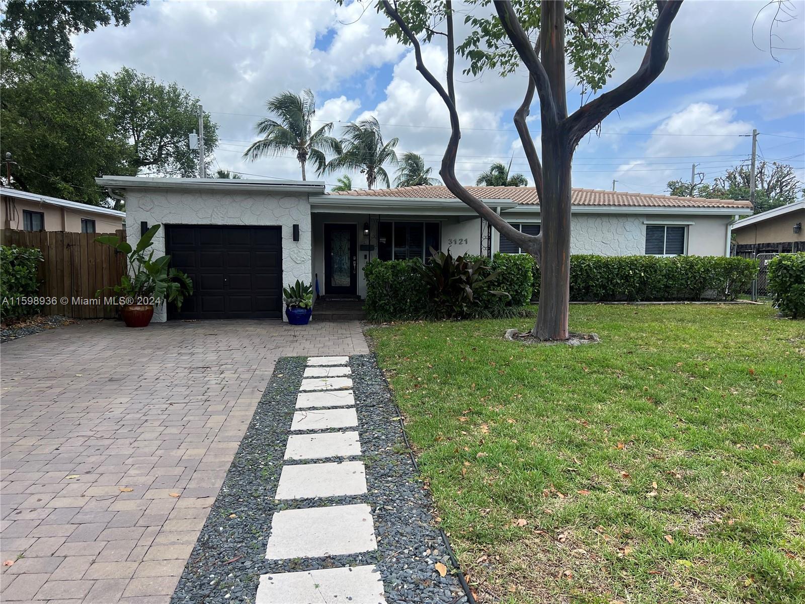 a front view of a house with a garden and trees