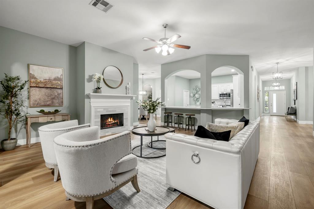 a living room with couches a fireplace and a large mirror with wooden floor