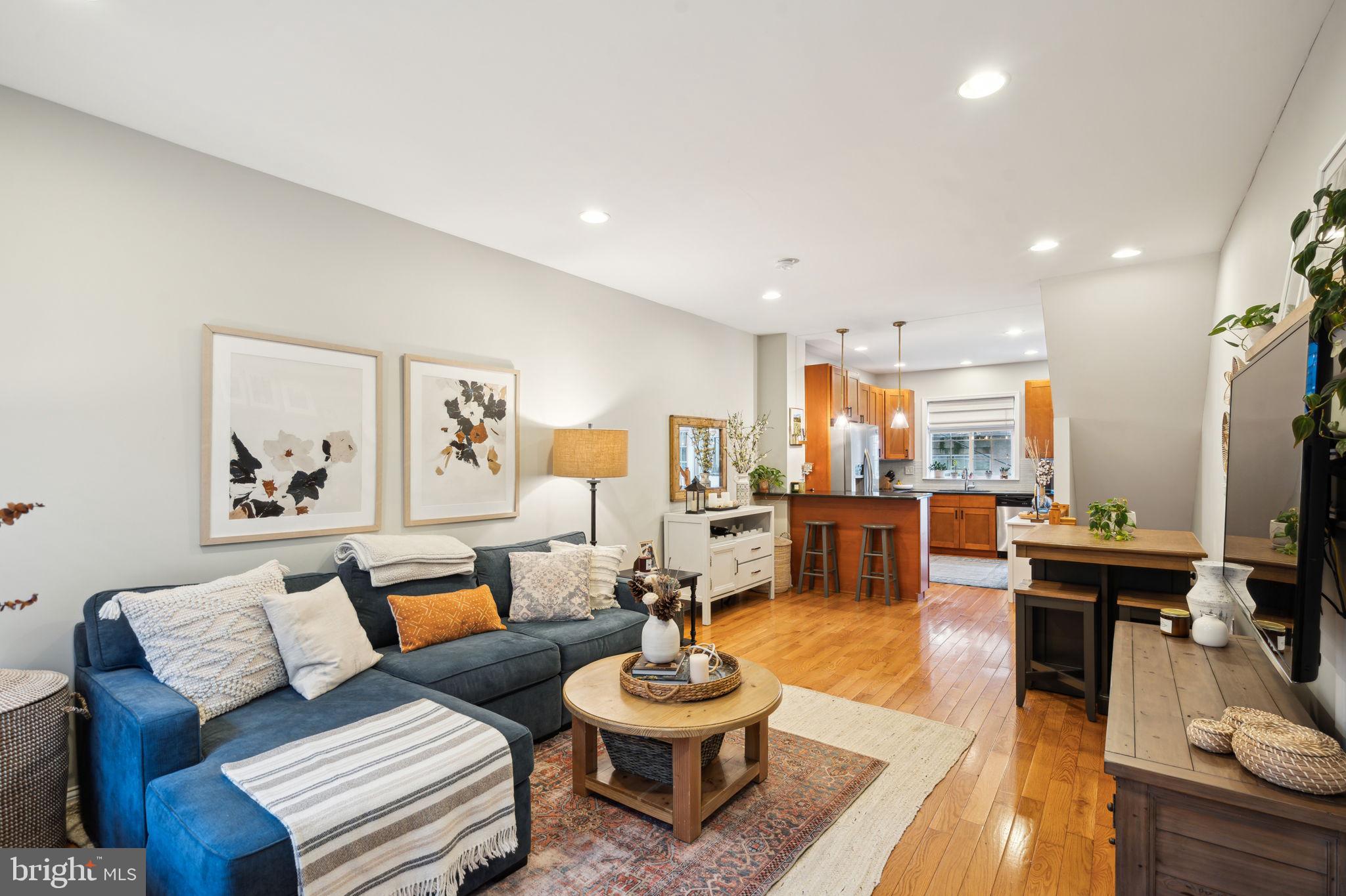 a living room with furniture and a dining table with wooden floor