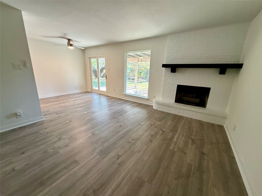 an empty room with wooden floor fireplace and windows