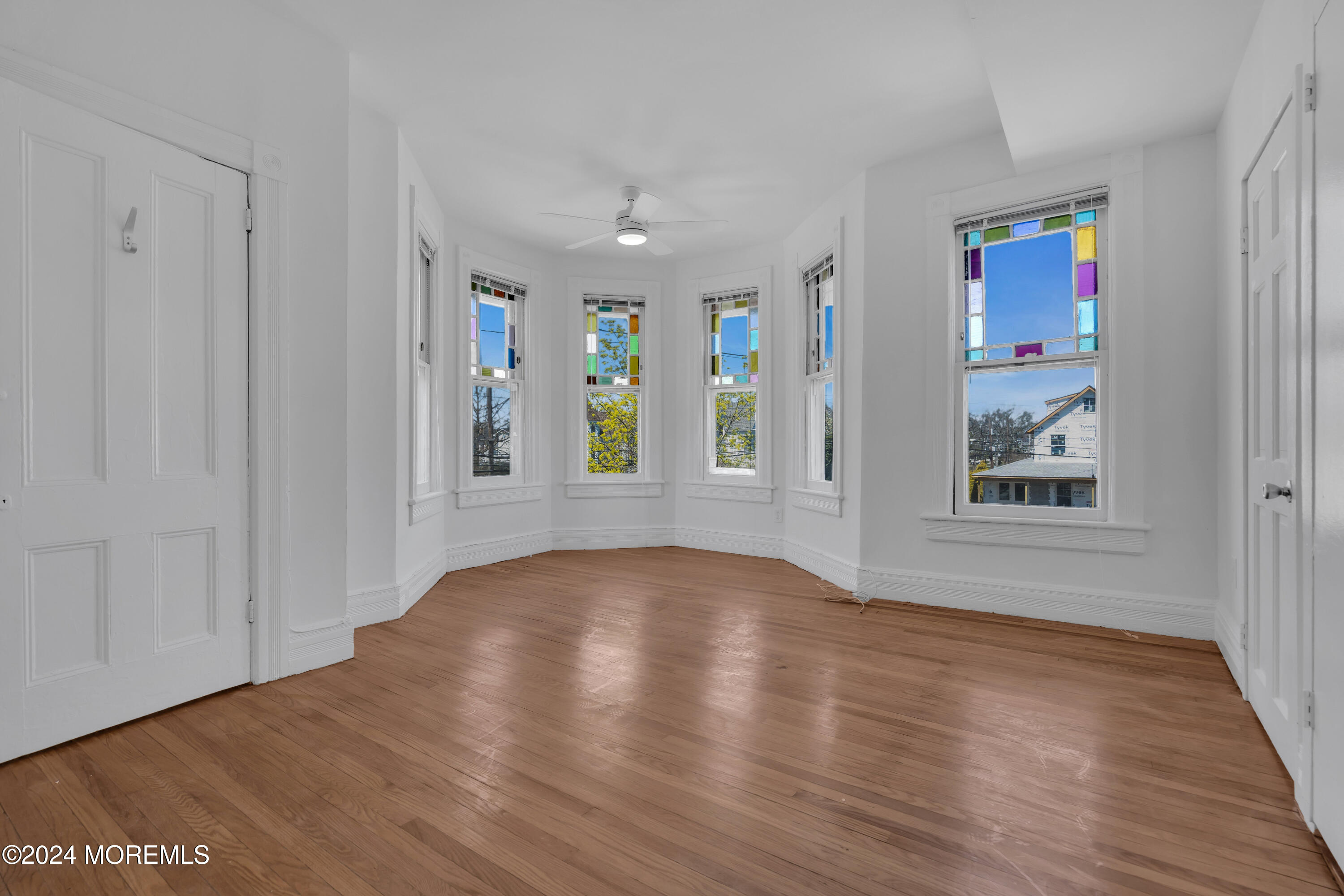 a view of an empty room with window and wooden floor