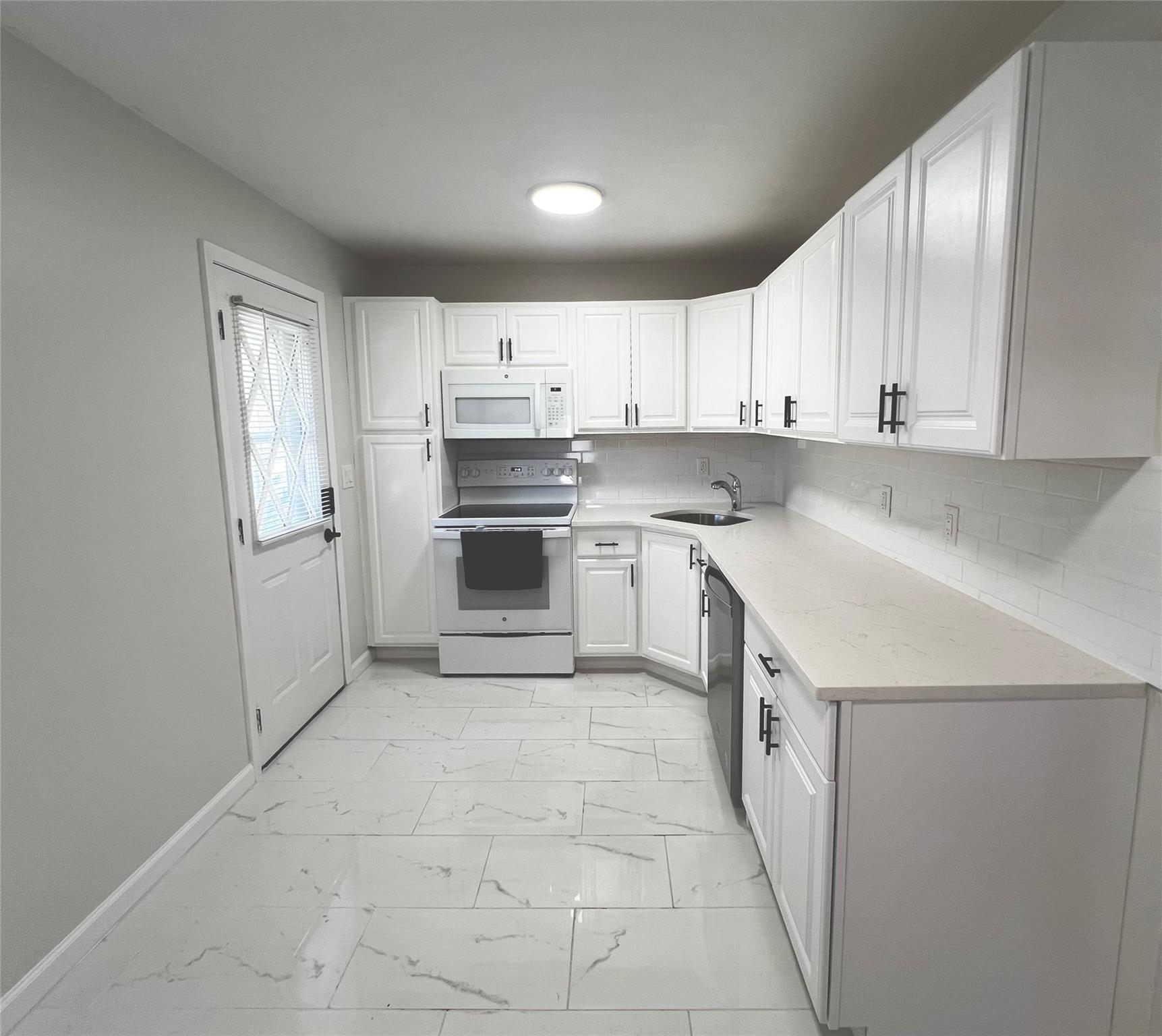 Kitchen featuring white cabinets, decorative backsplash, white appliances, and sink