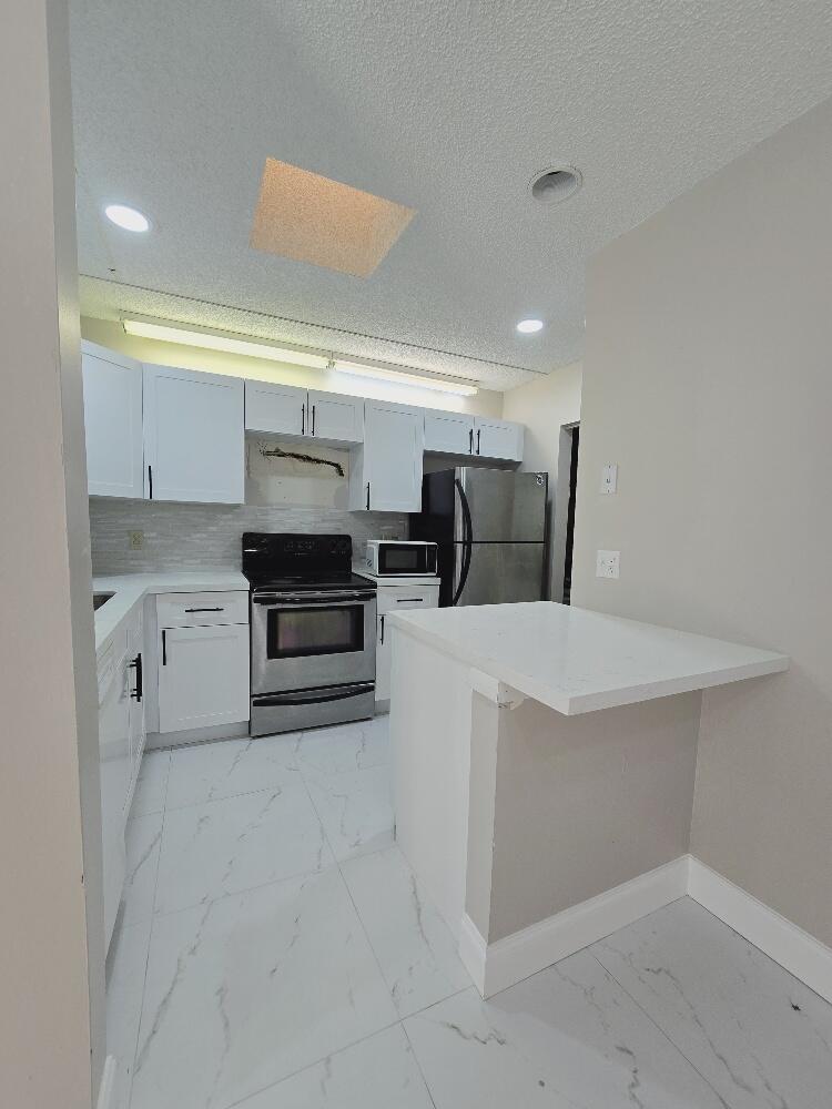 a kitchen with a refrigerator and white cabinets