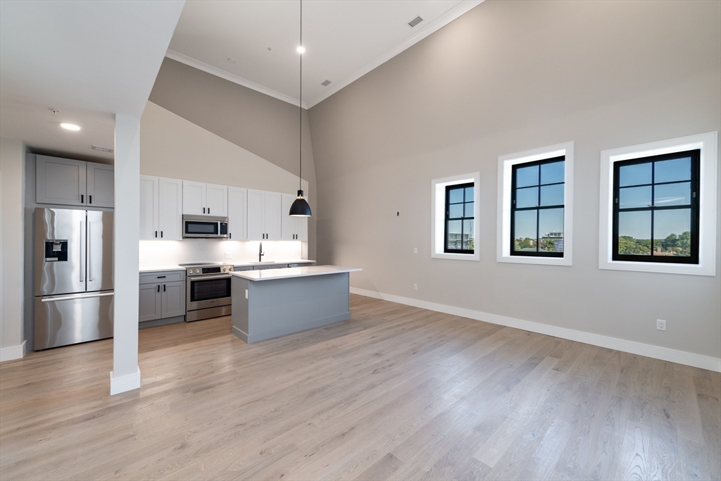 a large kitchen with stainless steel appliances kitchen island a large counter top and a wooden floor