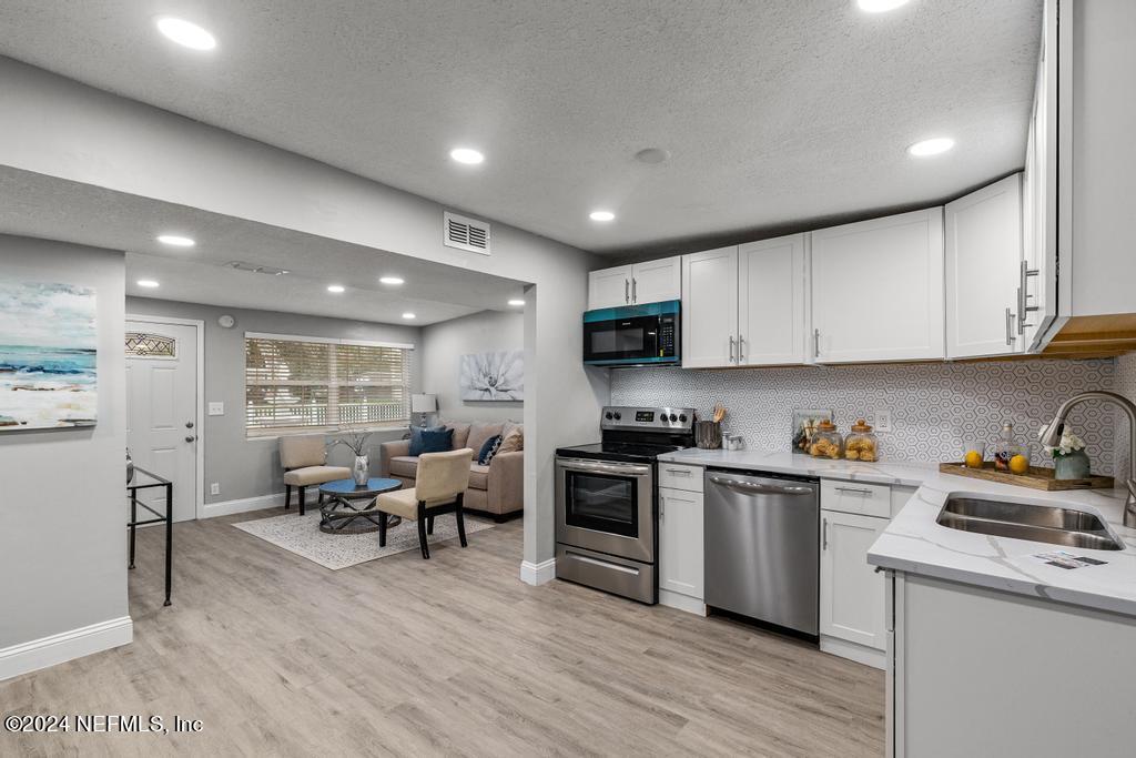 a kitchen with white cabinets and stainless steel appliances