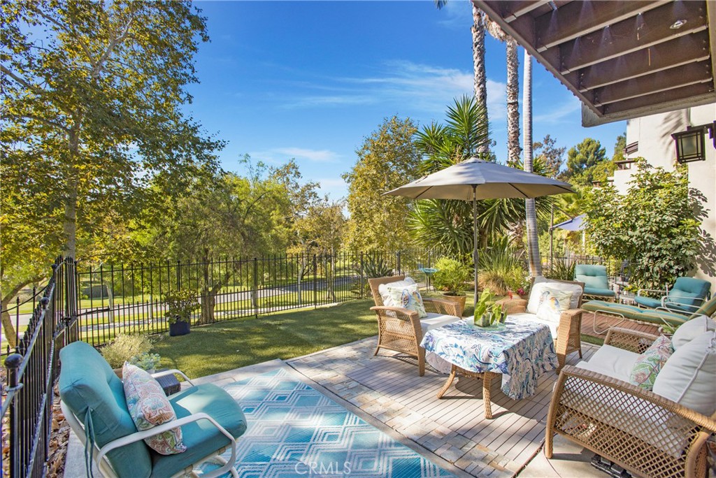 a view of a patio with couches table and chairs under an umbrella with a small yard