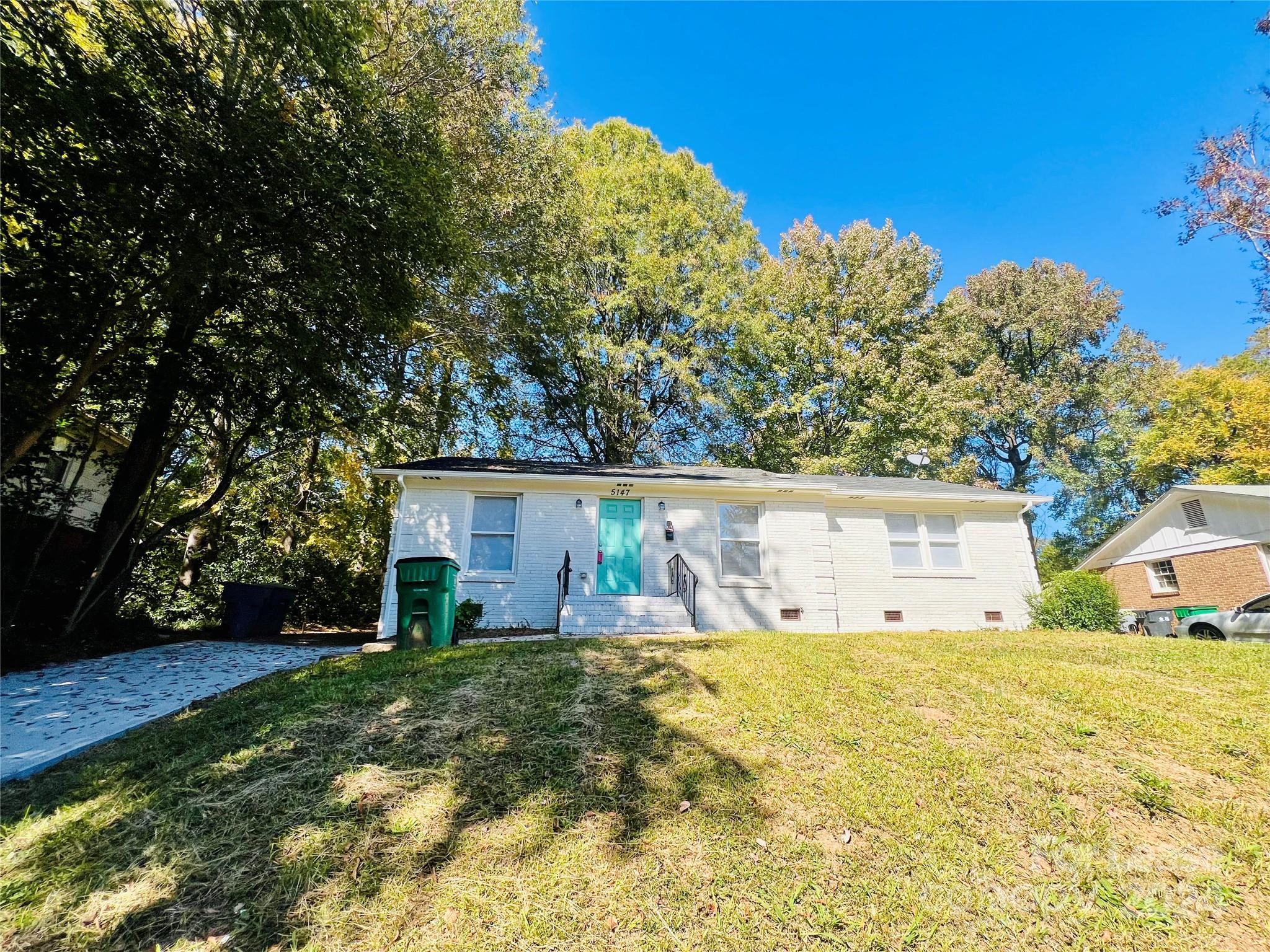 a front view of house with yard and trees in the background