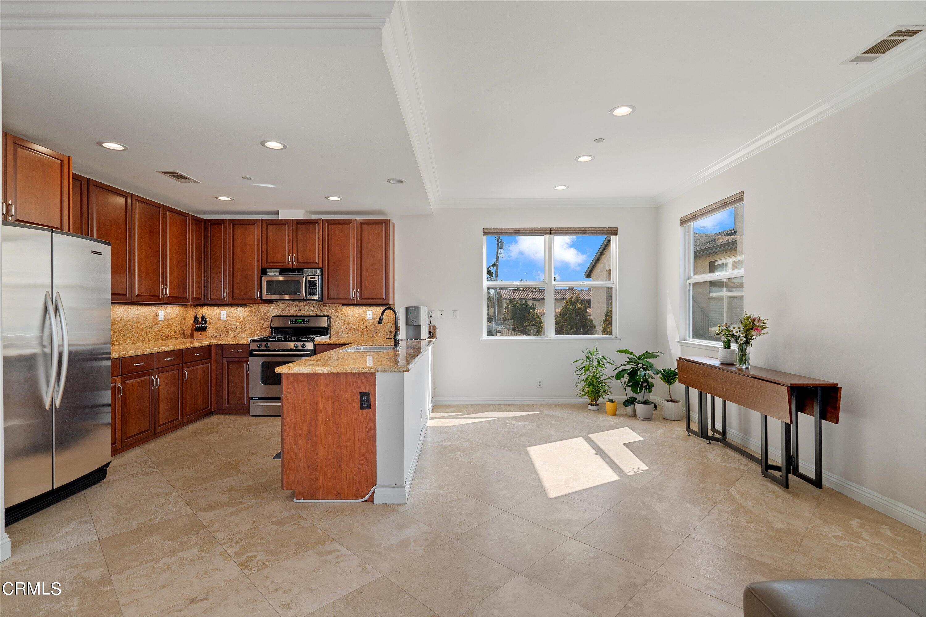 a kitchen with stainless steel appliances kitchen island granite countertop a refrigerator and a stove top oven