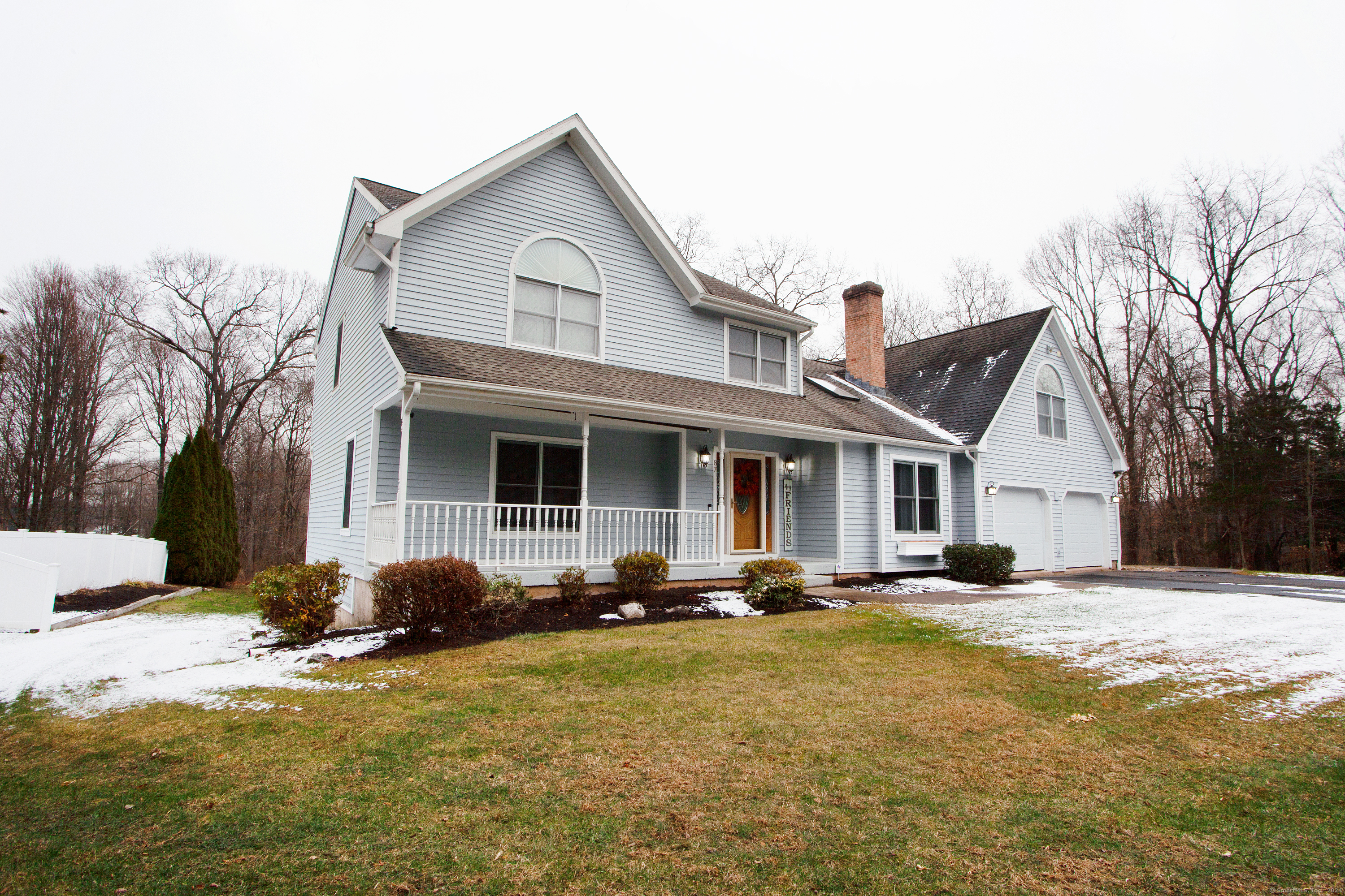 a view of a white house with a large windows and a yard with plants and trees