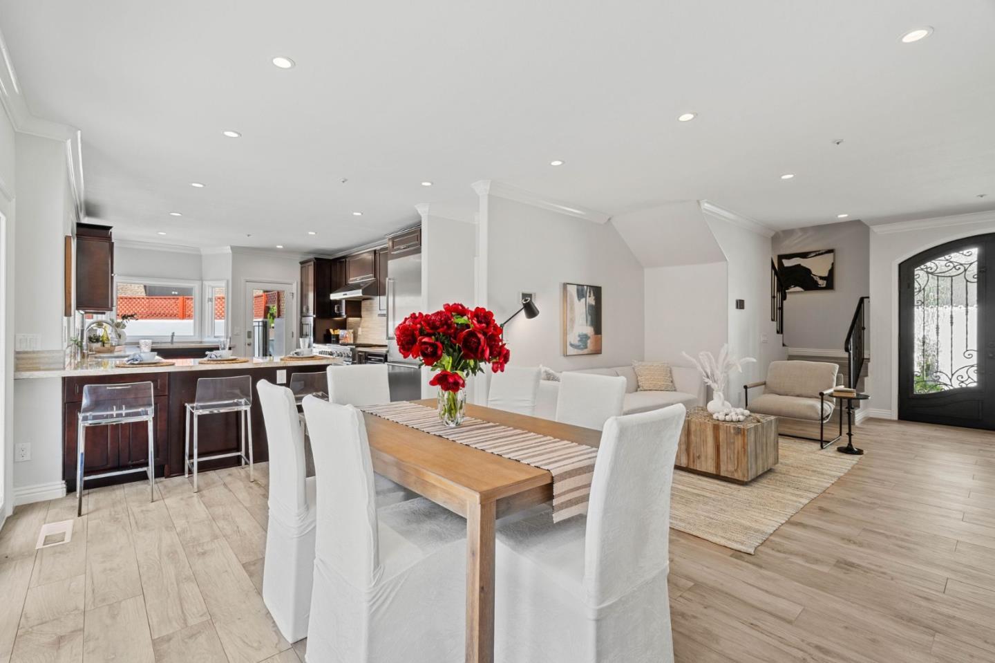 a dining room with kitchen island furniture a chandelier stainless steel appliances and wooden floor