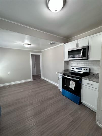 a kitchen with granite countertop wooden cabinets a stove and a microwave