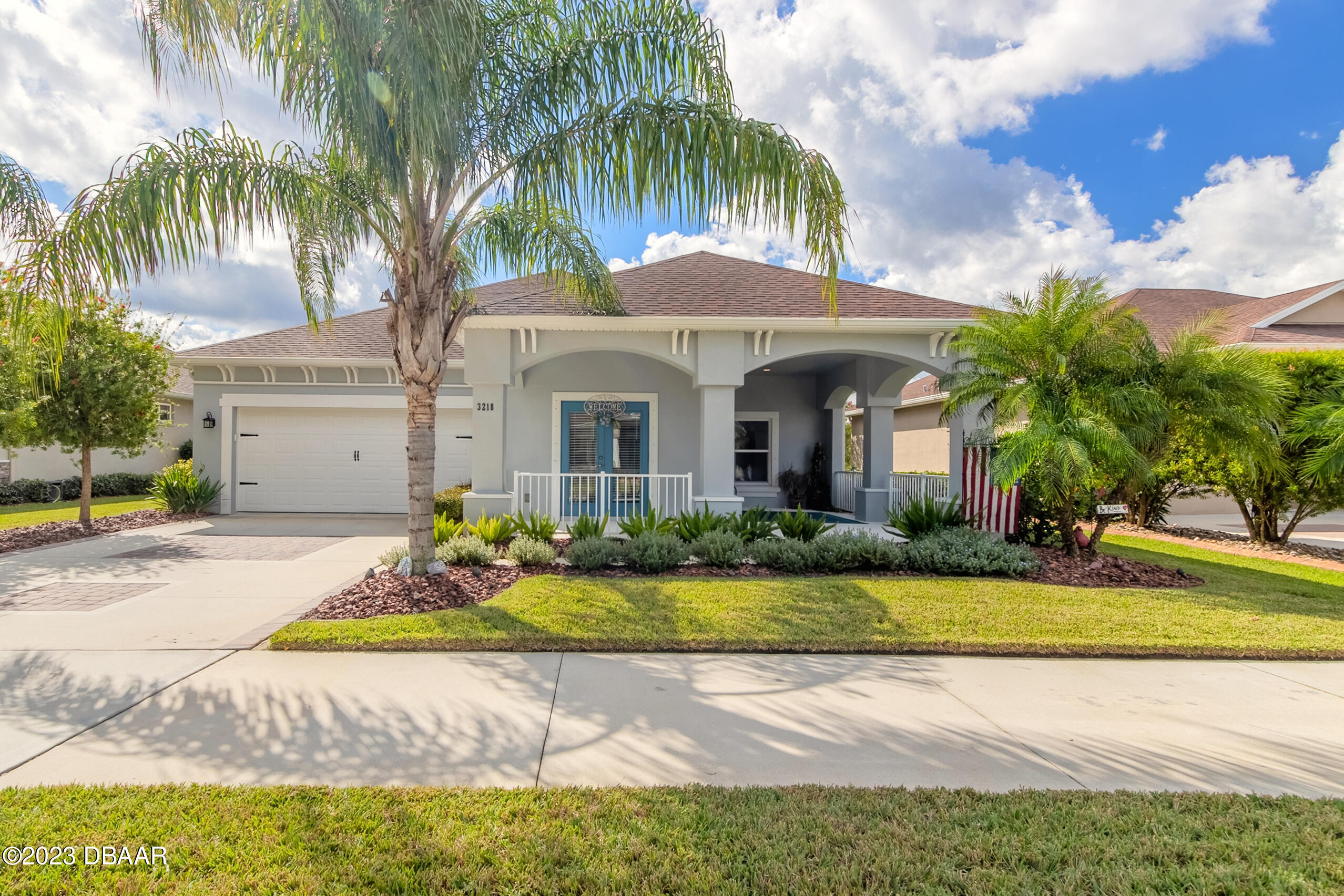 front view of house with a yard and palm trees