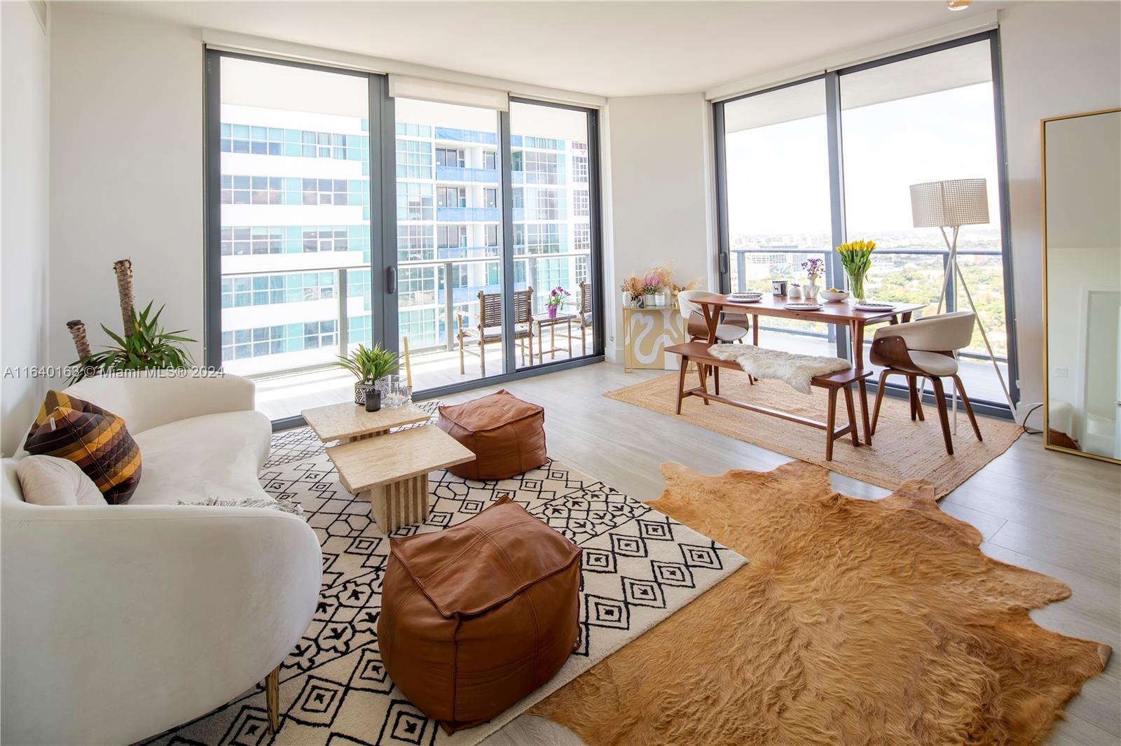 a living room with furniture large windows and wooden floor