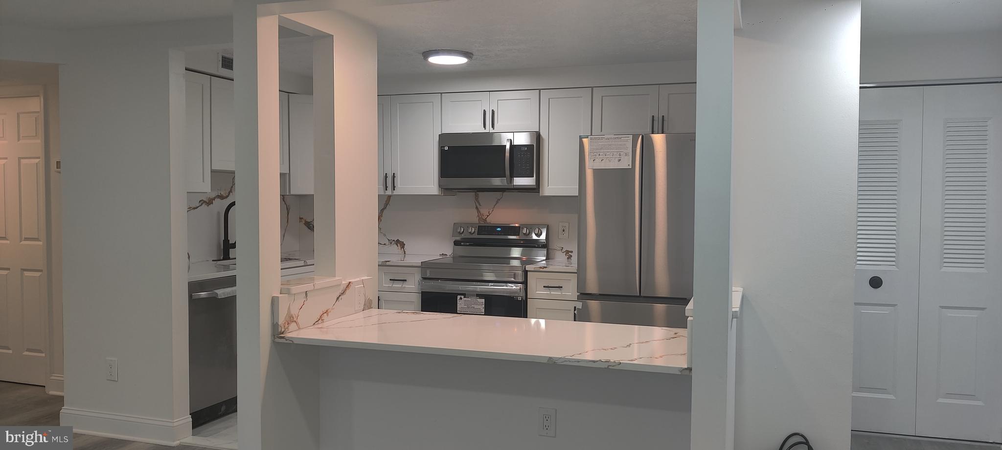 a kitchen with kitchen island a counter top space stainless steel appliances and cabinets