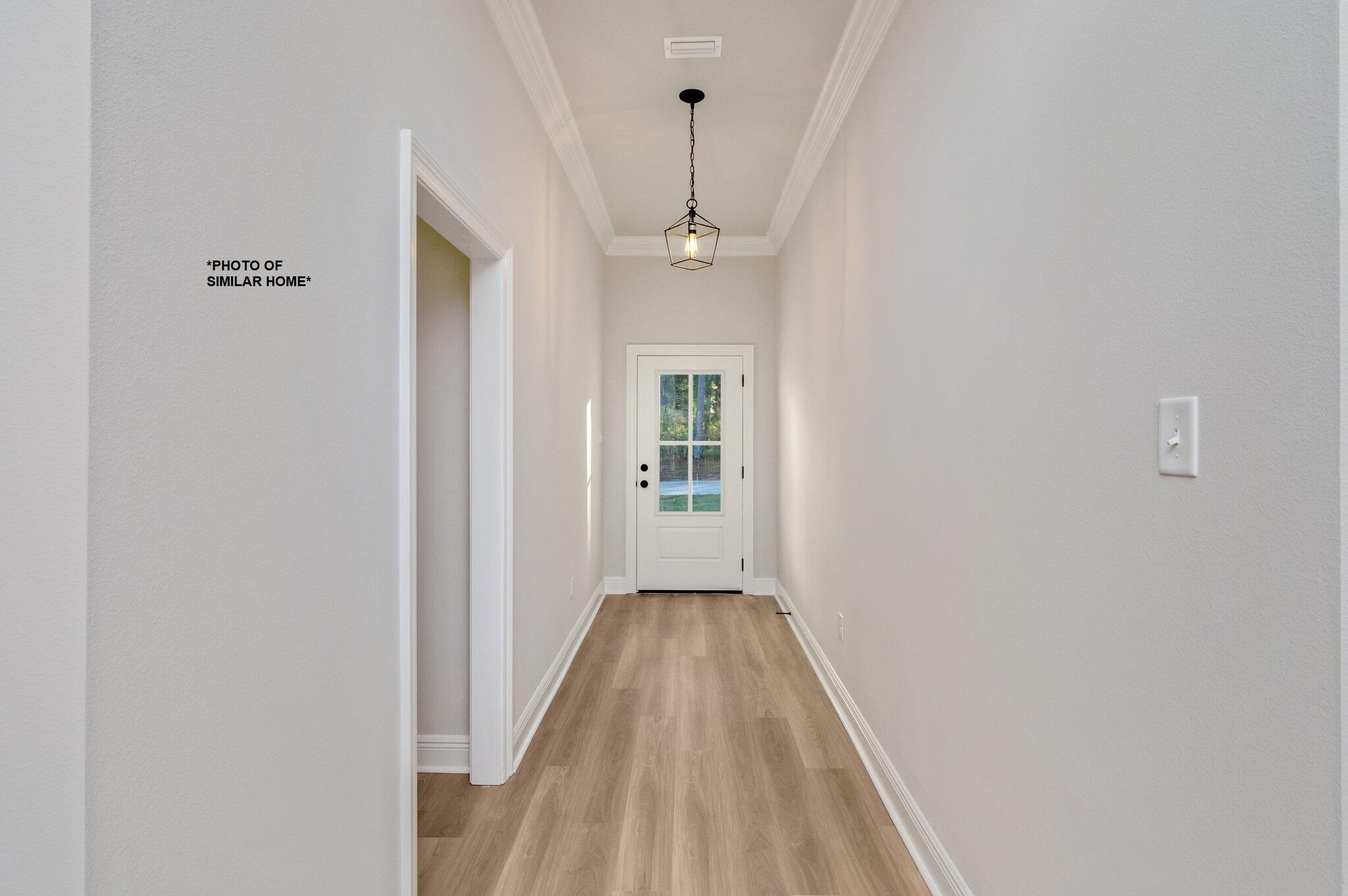 a view of a hallway with wooden floor and a bathroom