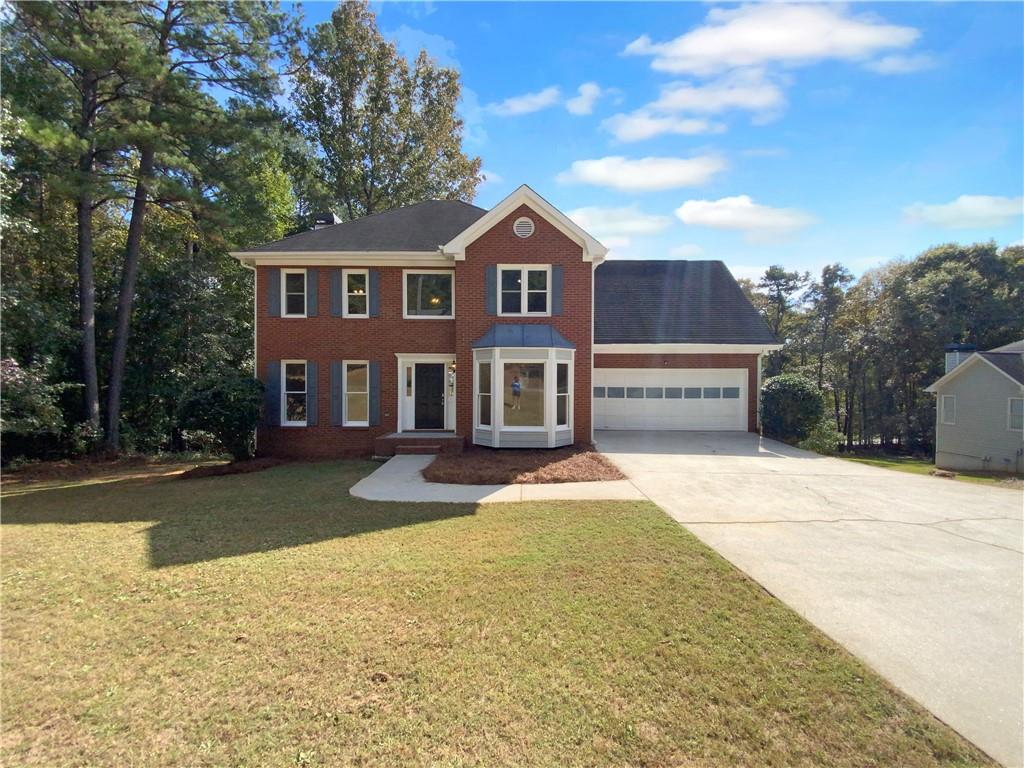 a front view of a house with yard and parking