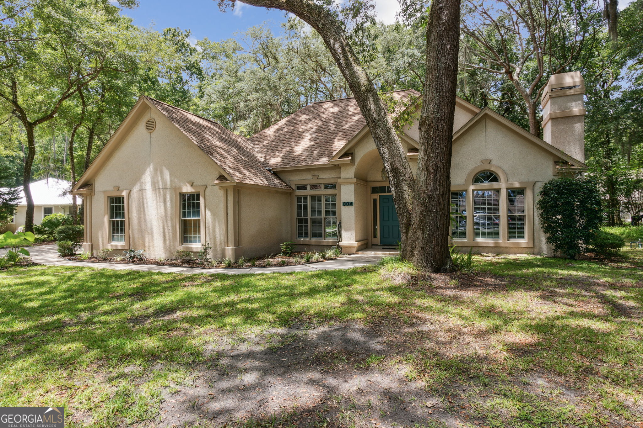 a front view of a house with a garden and trees