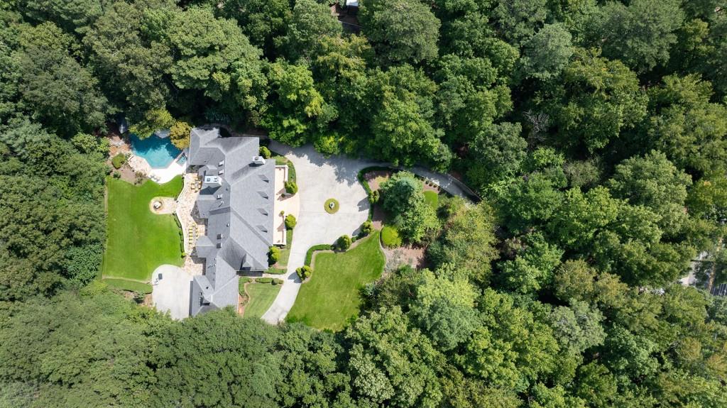 an aerial view of residential house with outdoor space and trees all around