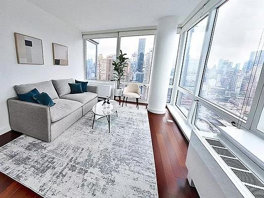 a living room with couches rug and a large window