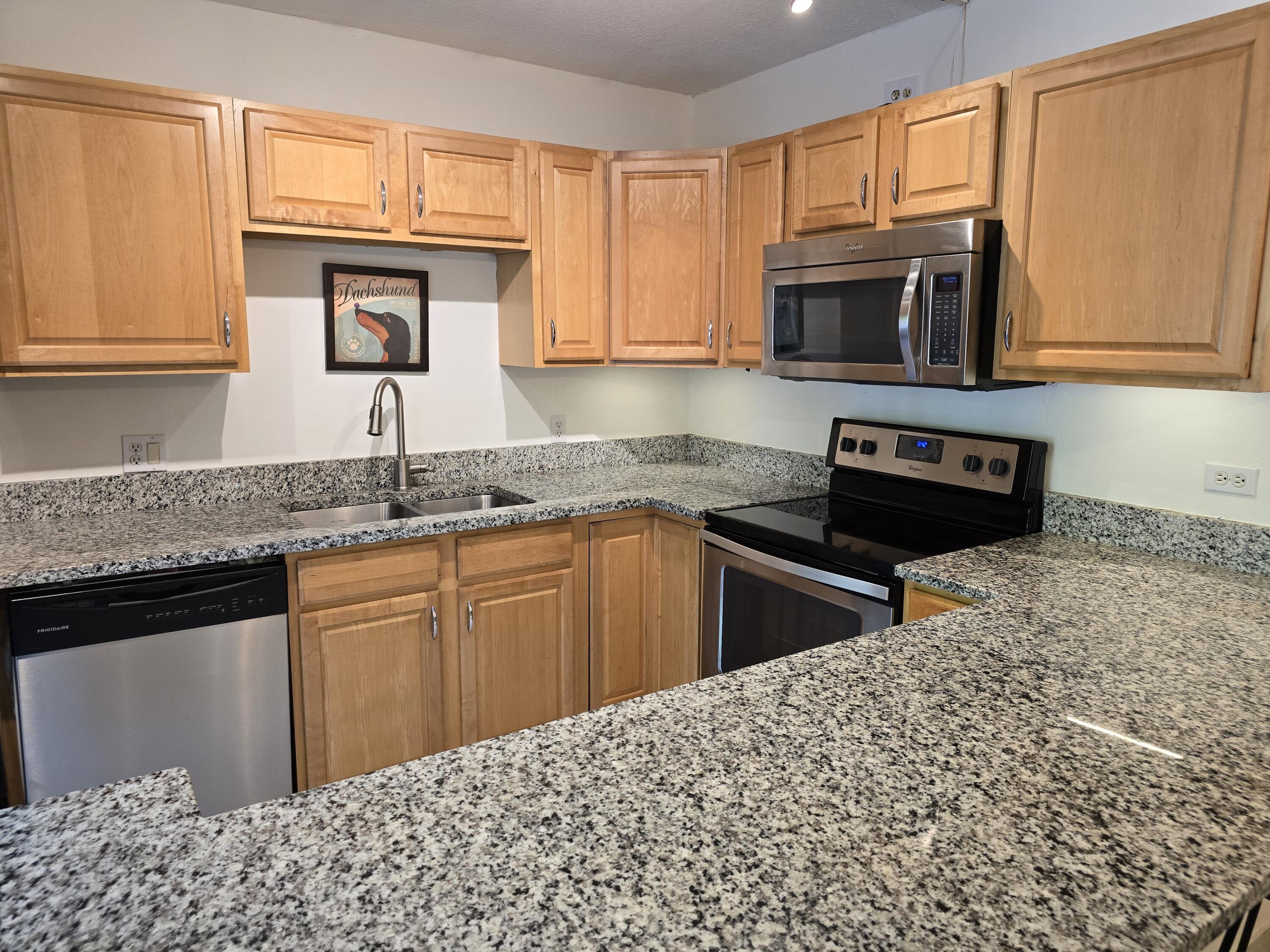 a kitchen with granite countertop cabinets stainless steel appliances a sink and a window