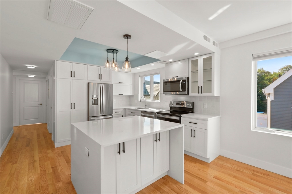 a kitchen with stainless steel appliances kitchen island a sink cabinets and wooden floor