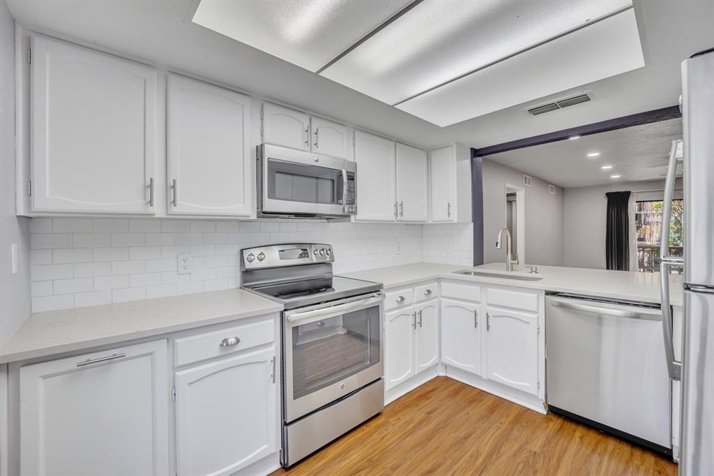 a kitchen with cabinets stainless steel appliances a sink and wooden floor