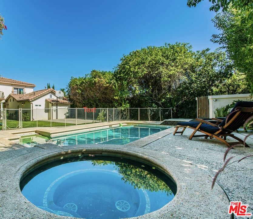 a view of a swimming pool with lawn chairs in front of a house