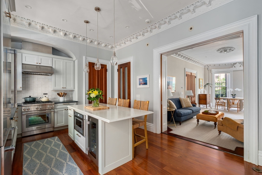 a large white kitchen with stainless steel appliances granite countertop a stove oven and a view of dining table