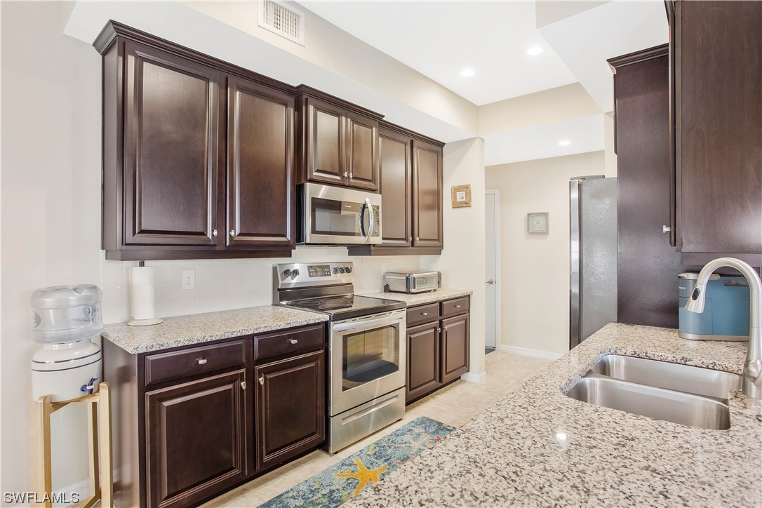 a kitchen with stainless steel appliances granite countertop a stove a sink and a refrigerator